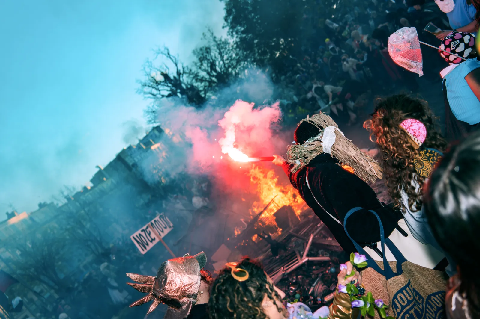 Foule festive au Carnaval de la Plaine, Marseille, avec un personnage brandissant un flambeau devant un feu de joie.
