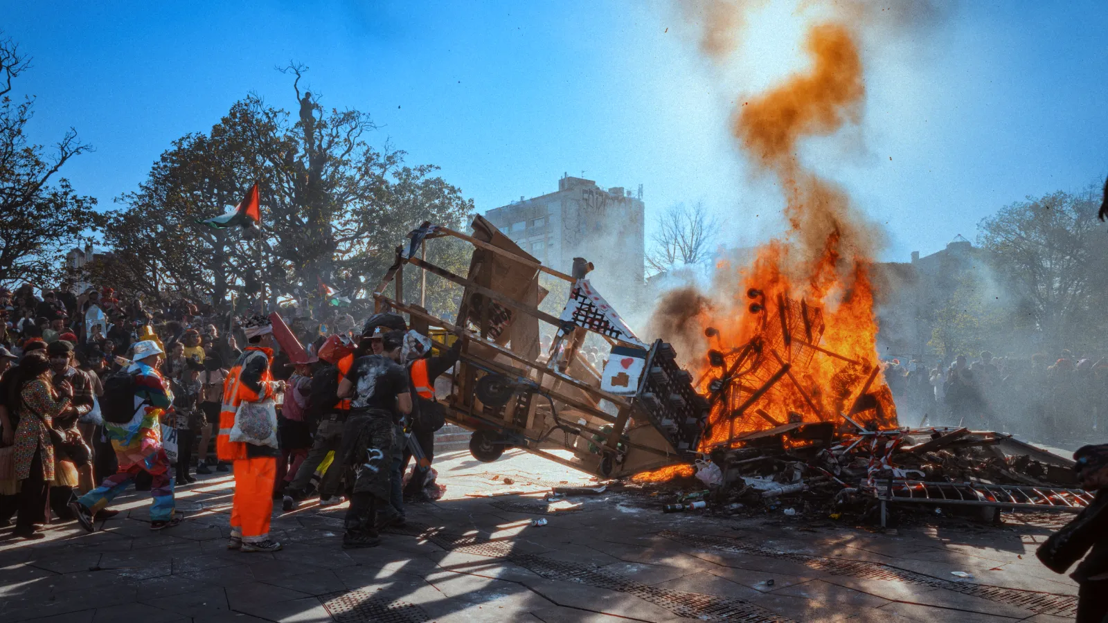 Des participants au carnaval entourent un grand feu de joie, avec des costumes colorés et une ambiance festive en plein air.