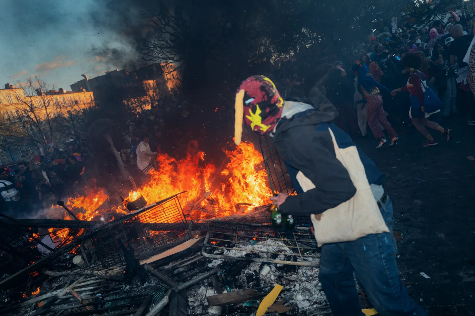 Foule festive au Carnaval de la Plaine, Marseille, avec un feu de joie et des participants en costumes colorés.