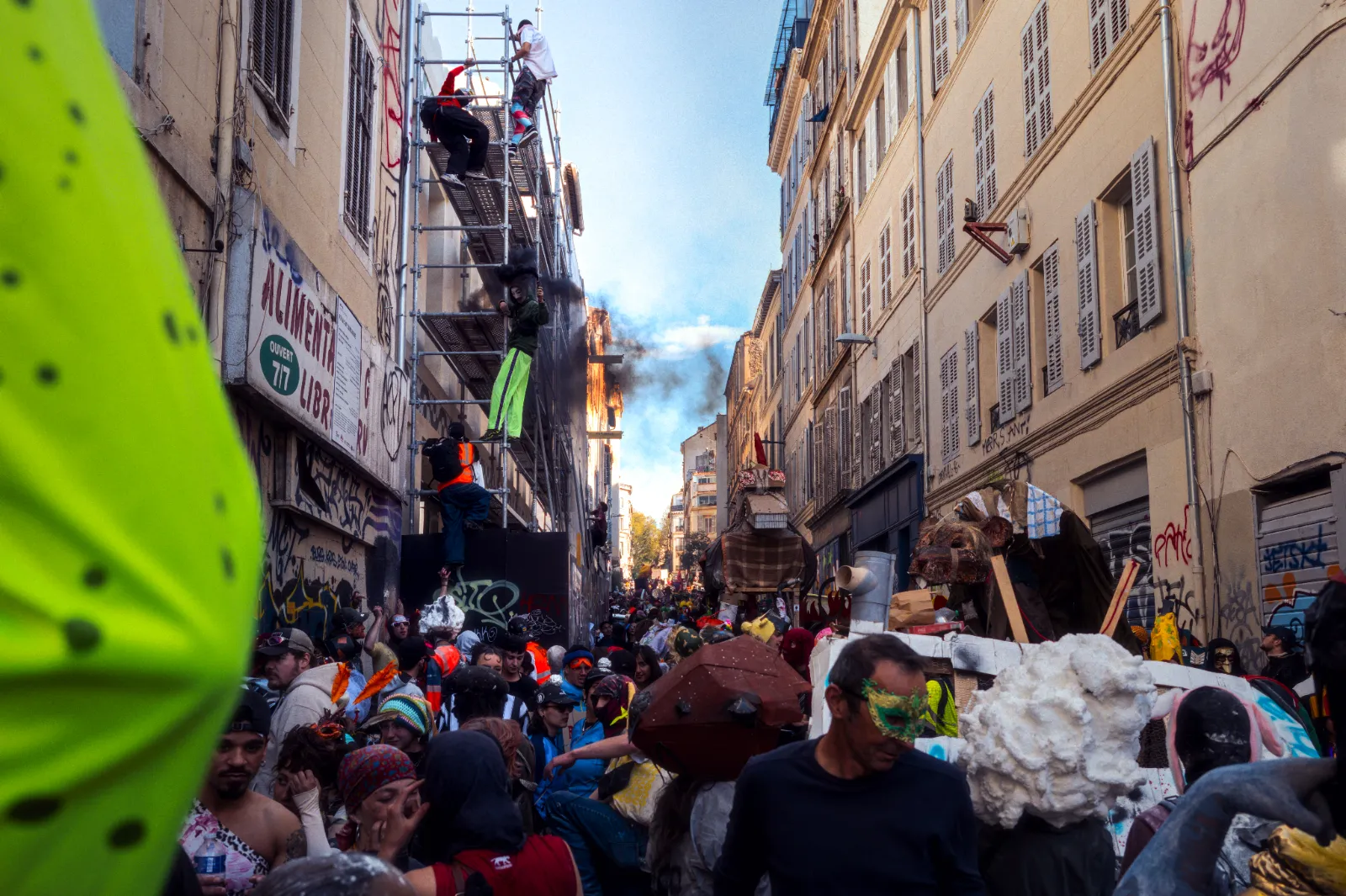 Foule festive au Carnaval de la Plaine, Marseille, avec costumes colorés, décorations et animations dans une rue animée.